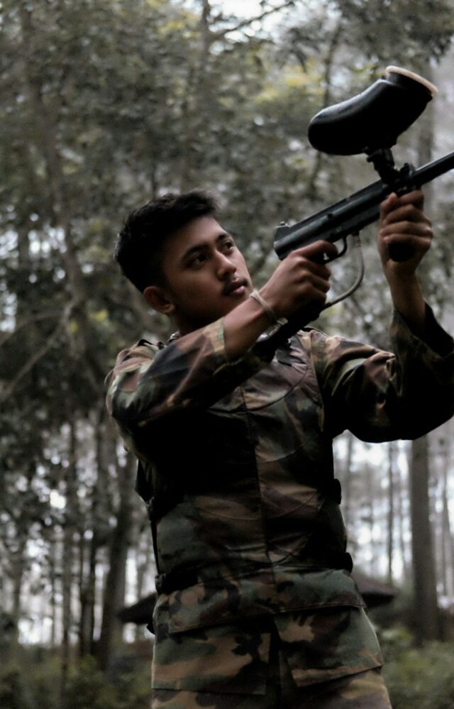 soldier holding paintball gun on forest