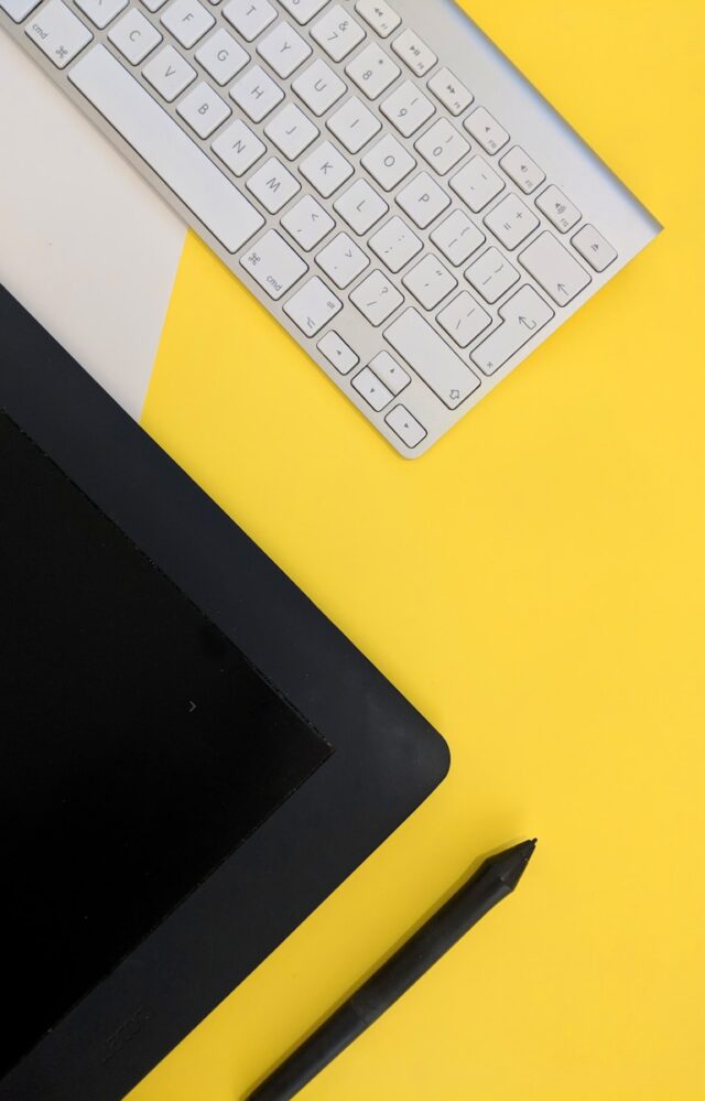 gray Apple wireless keyboard beside black tablet computer and stylus pen